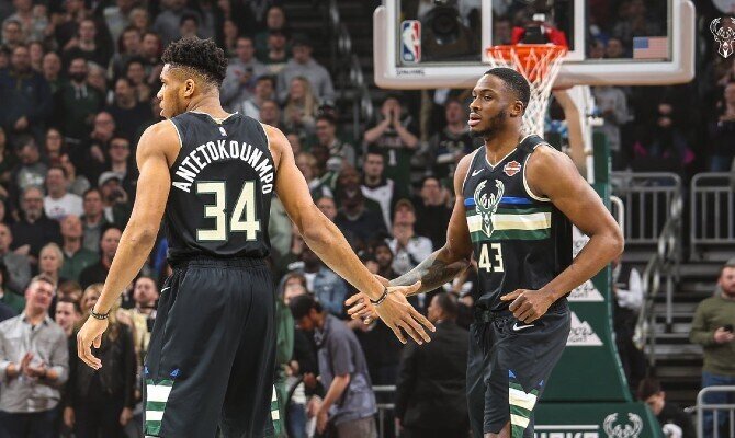 Antetokounmpo choca la mano con un compañero. Cuotas y picks Milwaukee Bucks vs Atlanta Hawks, NBA.