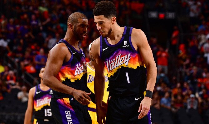 Devin Booker y Chris Paul conversan durante un partido. Cuotas Phoenix Suns vs Milwaukee Bucks, NBA.