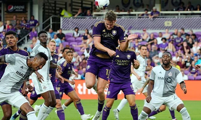 Jugadores de Orlando City y Toronto buscan el balón en un centro al área