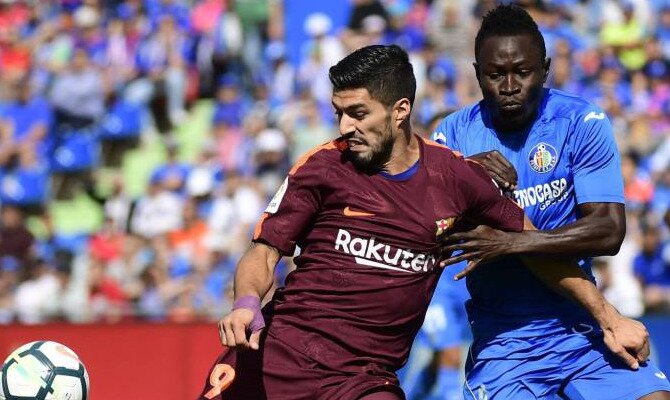 Luis Suárez (izquierda) pugna por un balón con Djené. Conoce los pronósticos del Barcelona Vs Getafe.