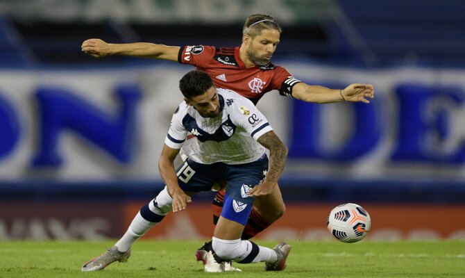 Imagen de dos jugadores luchando por el balón. Revisa los picks del LDU Quito vs Velez Sarsfield